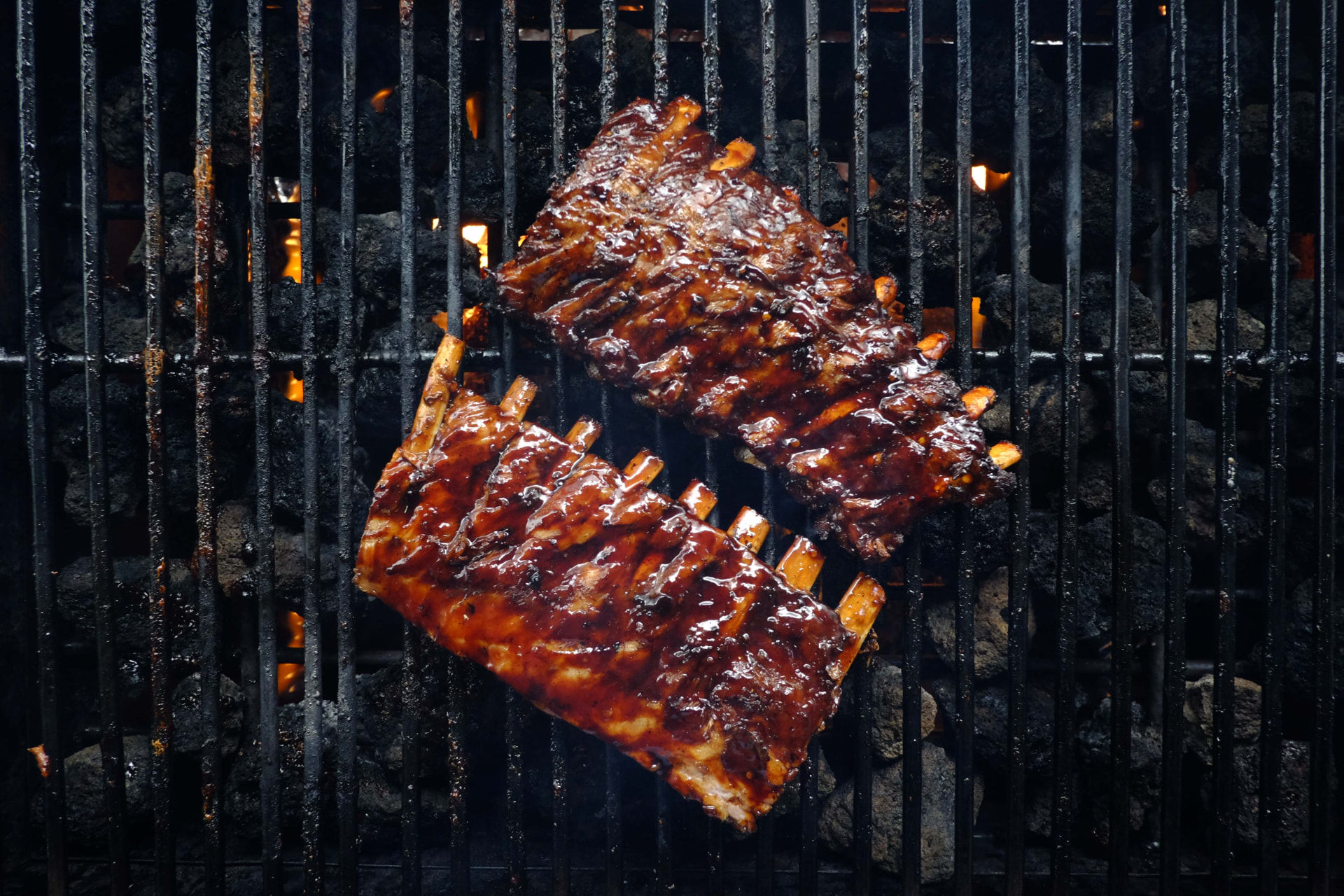 Glazed Hog Wild pork ribs cooking over the barbecue grill